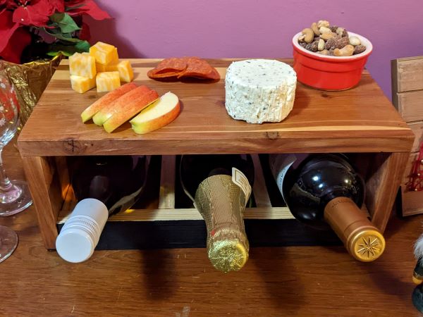 wine serving box with charcuterie spread and three wine bottles