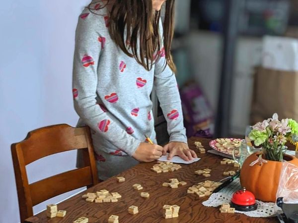 girl sorting scrabble tiles at antique kitchen table